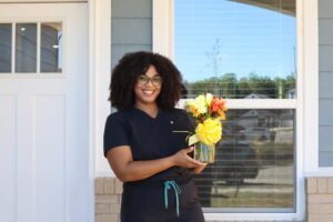 Houston Habitat Family Partner holding a vase of colorful flowers in front of new home